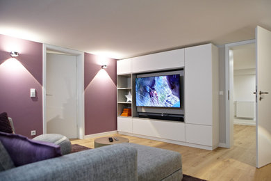 Modernes Wohnzimmer mit grauer Wandfarbe, hellem Holzboden, TV-Wand und beigem Boden in Düsseldorf