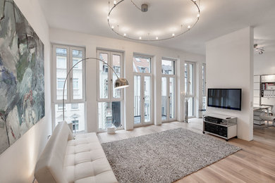 Großes, Repräsentatives, Offenes Skandinavisches Wohnzimmer ohne Kamin mit weißer Wandfarbe, hellem Holzboden, TV-Wand und beigem Boden in Köln