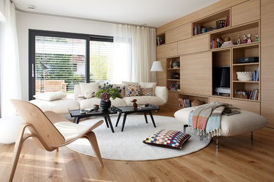 Cette photo montre une grande salle de séjour tendance ouverte avec un sol en bois brun, un téléviseur dissimulé, un mur blanc et aucune cheminée.