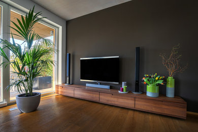 Ejemplo de sala de estar cerrada contemporánea grande con paredes grises, suelo de madera pintada, televisor independiente y suelo marrón