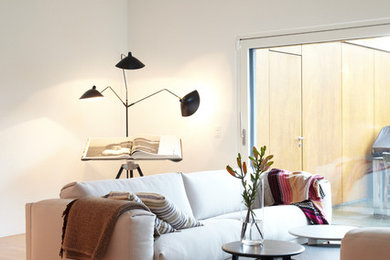 Großes, Offenes Nordisches Wohnzimmer mit hellem Holzboden und weißer Wandfarbe in Sonstige