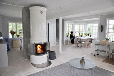 Ejemplo de sala de estar abierta escandinava grande con paredes blancas, suelo de madera clara, todas las chimeneas, marco de chimenea de baldosas y/o azulejos y suelo blanco