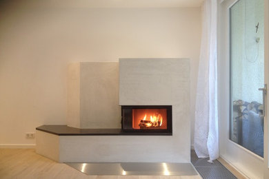 Imagen de salón actual con chimenea de esquina, marco de chimenea de yeso y suelo beige