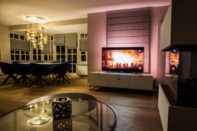 Modernes Wohnzimmer mit braunem Holzboden und Hängekamin in Bremen