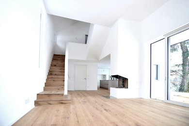Источник вдохновения для домашнего уюта: большая двухуровневая гостиная комната в современном стиле с белыми стенами, светлым паркетным полом и фасадом камина из металла без камина