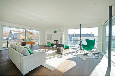 Example of a large trendy enclosed medium tone wood floor and brown floor family room design in Munich with white walls, a corner fireplace, a plaster fireplace and no tv