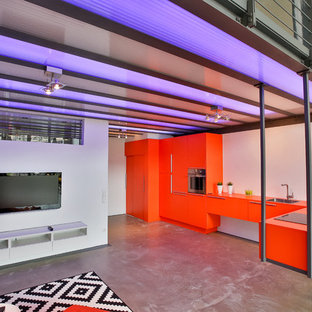 Großes, Offenes Industrial Wohnzimmer ohne Kamin mit weißer Wandfarbe, Betonboden, Wand-TV und grauem Boden in Köln