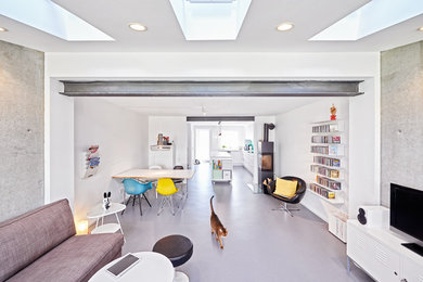 Großes, Offenes Modernes Wohnzimmer mit weißer Wandfarbe, Betonboden, Kaminofen und freistehendem TV in Stuttgart