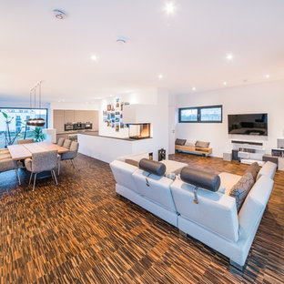 Großes, Repräsentatives, Offenes Modernes Wohnzimmer mit weißer Wandfarbe, Bambusparkett, Tunnelkamin, verputzter Kaminumrandung, Wand-TV und braunem Boden in Frankfurt am Main