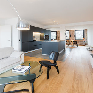 Repräsentatives, Geräumiges Industrial Wohnzimmer im Loft-Stil mit weißer Wandfarbe, braunem Holzboden, Gaskamin, verputzter Kaminumrandung, Wand-TV und braunem Boden in Essen