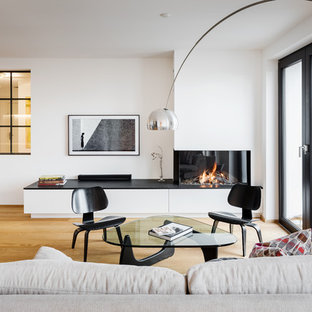 Mittelgroßes, Offenes Modernes Wohnzimmer mit weißer Wandfarbe, hellem Holzboden, Gaskamin, Wand-TV, braunem Boden und verputzter Kaminumrandung in Essen