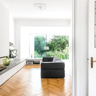 Mittelgroßes, Offenes Modernes Wohnzimmer mit weißer Wandfarbe, hellem Holzboden, Eckkamin, Kaminumrandung aus Metall und Wand-TV in Hamburg