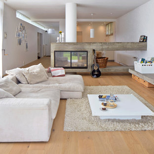 Großes Industrial Musikzimmer mit braunem Holzboden, braunem Boden, weißer Wandfarbe, Tunnelkamin und freistehendem TV in Sonstige