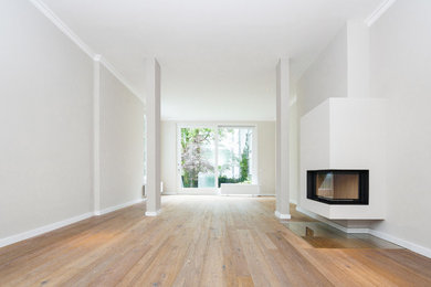 Mittelgroßes, Fernseherloses Modernes Wohnzimmer im Loft-Stil mit beiger Wandfarbe, braunem Holzboden, Hängekamin und verputzter Kaminumrandung in Hamburg