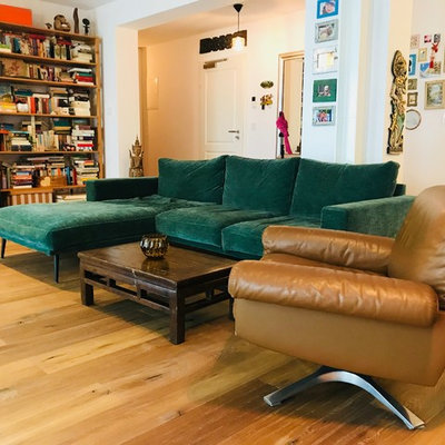 Example of a mid-sized eclectic open concept medium tone wood floor and brown floor family room library design in Munich with white walls and no fireplace