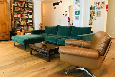 Modelo de sala de estar con biblioteca abierta bohemia de tamaño medio sin chimenea con paredes blancas, suelo de madera en tonos medios y suelo marrón