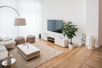 Kleines, Offenes Modernes Wohnzimmer ohne Kamin mit weißer Wandfarbe, braunem Holzboden, TV-Wand und braunem Boden in Berlin