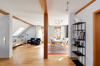 Geräumiges, Fernseherloses, Offenes Modernes Wohnzimmer ohne Kamin mit grauer Wandfarbe, braunem Holzboden und braunem Boden in Stuttgart