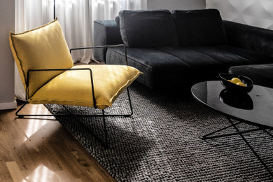 Geräumiges, Offenes Modernes Wohnzimmer mit grauer Wandfarbe, hellem Holzboden, braunem Boden und Wandpaneelen in Berlin
