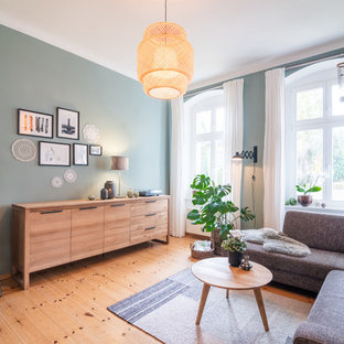 Großes Nordisches Wohnzimmer mit grüner Wandfarbe, braunem Holzboden und braunem Boden in Berlin