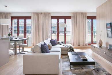 Mittelgroßes, Offenes Modernes Wohnzimmer mit weißer Wandfarbe, braunem Holzboden, TV-Wand und braunem Boden in Berlin