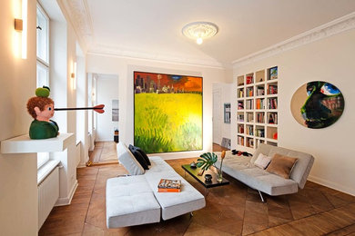 Imagen de sala de estar con biblioteca abierta bohemia pequeña sin chimenea y televisor con paredes beige, suelo de madera en tonos medios y suelo marrón