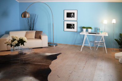 Diseño de salón actual sin chimenea con paredes azules y suelo de madera clara