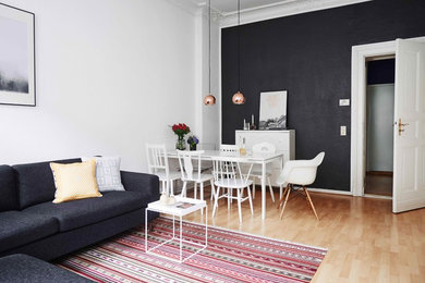 Imagen de sala de estar cerrada bohemia sin chimenea con paredes negras y suelo de madera clara