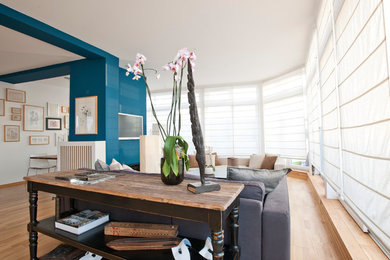 Großes, Offenes Modernes Wohnzimmer mit Hausbar, blauer Wandfarbe, braunem Holzboden, TV-Wand und braunem Boden in Berlin