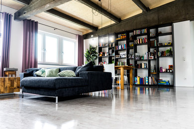 Diseño de sala de estar con biblioteca actual grande sin chimenea con paredes blancas, suelo de cemento y suelo gris