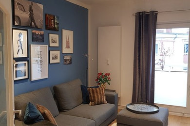 Mittelgroßes, Abgetrenntes Wohnzimmer mit weißer Wandfarbe, braunem Holzboden und freistehendem TV in Köln