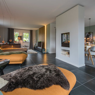 Offenes, Geräumiges, Repräsentatives Modernes Wohnzimmer mit weißer Wandfarbe, Tunnelkamin, verputzter Kaminumrandung, schwarzem Boden und freistehendem TV in Hamburg
