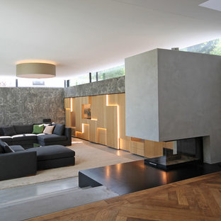 Großes Modernes Wohnzimmer im Loft-Stil mit grauer Wandfarbe, Betonboden, Kaminumrandung aus Beton, verstecktem TV, grauem Boden und Tunnelkamin in München