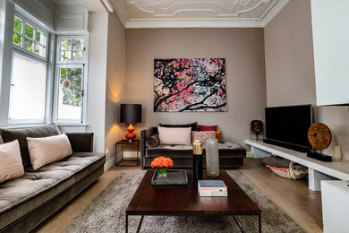 Geräumiges, Offenes Modernes Wohnzimmer mit beiger Wandfarbe, gebeiztem Holzboden, Eckkamin, verputzter Kaminumrandung, freistehendem TV und braunem Boden