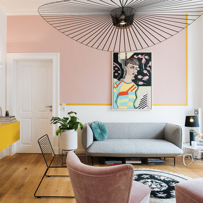 Example of a mid-sized eclectic enclosed medium tone wood floor and brown floor family room design in Cologne with white walls, no fireplace and a tv stand