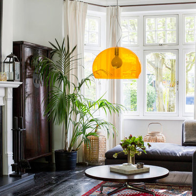 Example of a mid-sized eclectic open concept dark wood floor and brown floor family room design in London with white walls, a wood stove, no tv and a stone fireplace