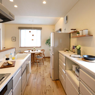 他の地域の中くらいのモダンスタイルのおしゃれなキッチン (一体型シンク、白いキャビネット、人工大理石カウンター、白いキッチンパネル、ガラス板のキッチンパネル、無垢フローリング、白いキッチンカウンター、フラットパネル扉のキャビネット、茶色い床) の写真