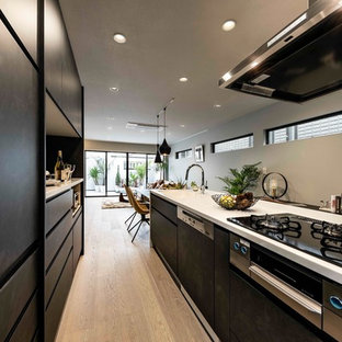 Modelo de cocina lineal, actual, de tamaño medio, cerrada, con fregadero integrado, puertas de armario negras, encimera de vidrio reciclado, salpicadero marrón, electrodomésticos con paneles, suelo de contrachapado, una isla, suelo gris, encimeras blancas y armarios con paneles lisos