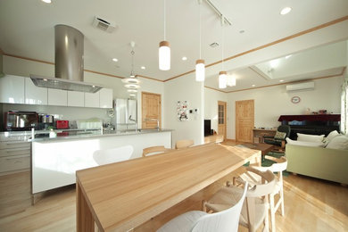 他の地域にあるカントリー風のおしゃれなキッチン (一体型シンク、白いキャビネット、ステンレスカウンター、白いキッチンパネル、黒い調理設備、ベージュの床) の写真