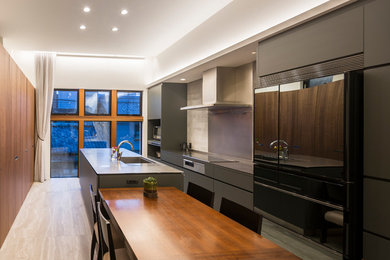 Cette photo montre une cuisine parallèle moderne avec un évier 1 bac, un placard à porte plane, des portes de placard grises, parquet peint, îlot, un sol beige et un plan de travail gris.