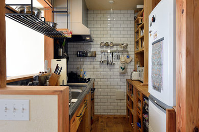Modelo de cocina lineal romántica cerrada con encimera de acero inoxidable, salpicadero metalizado, salpicadero de azulejos tipo metro y suelo de madera oscura