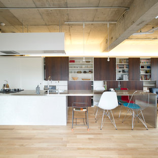 Idee per una cucina industriale con penisola, top in acciaio inossidabile, parquet chiaro, lavello integrato, ante in legno bruno, paraspruzzi a effetto metallico, elettrodomestici neri, pavimento beige e top bianco