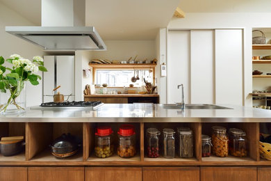 Foto di una piccola cucina moderna con lavello integrato, ante marroni, top in acciaio inossidabile, elettrodomestici in acciaio inossidabile, pavimento in legno massello medio e pavimento beige