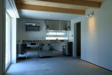 他の地域にある中くらいなモダンスタイルのおしゃれなI型キッチン (オープンシェルフ、ステンレスキャビネット、ステンレスカウンター、コンクリートの床、グレーの床、表し梁) の写真
