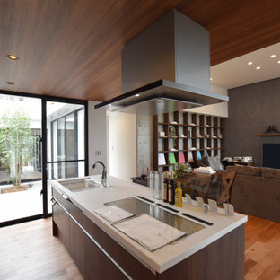 Photo of a modern single-wall open plan kitchen in Other with an undermount sink, beaded inset cabinets, dark wood cabinets, solid surface benchtops, plywood floors, with island, brown floor, white benchtop and wallpaper.