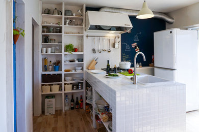 Foto på ett litet industriellt linjärt kök, med en enkel diskho, öppna hyllor, kaklad bänkskiva, mellanmörkt trägolv, en halv köksö och brunt golv