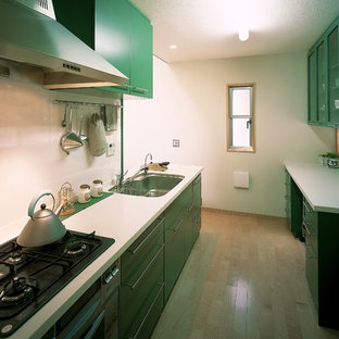 Small contemporary single-wall open plan kitchen in Tokyo with an undermount sink, flat-panel cabinets, green cabinets, solid surface benchtops, white splashback, slate splashback, stainless steel appliances, plywood floors, a peninsula, brown floor and white benchtop.
