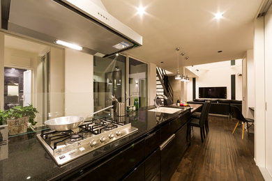 Idee per una cucina moderna con ante nere, pavimento in legno massello medio, pavimento marrone, top in granito, paraspruzzi con lastra di vetro e elettrodomestici in acciaio inossidabile