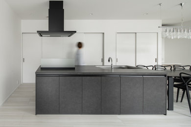 Идея дизайна: прямая кухня-гостиная в стиле модернизм с врезной мойкой, плоскими фасадами, серыми фасадами, островом, серым полом и серой столешницей