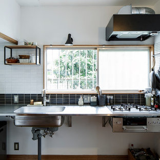 This is an example of an asian l-shaped kitchen in Yokohama with an integrated sink, louvered cabinets, stainless steel benchtops, black splashback, mosaic tile splashback, stainless steel appliances, brown floor, grey benchtop, dark wood cabinets and dark hardwood floors.